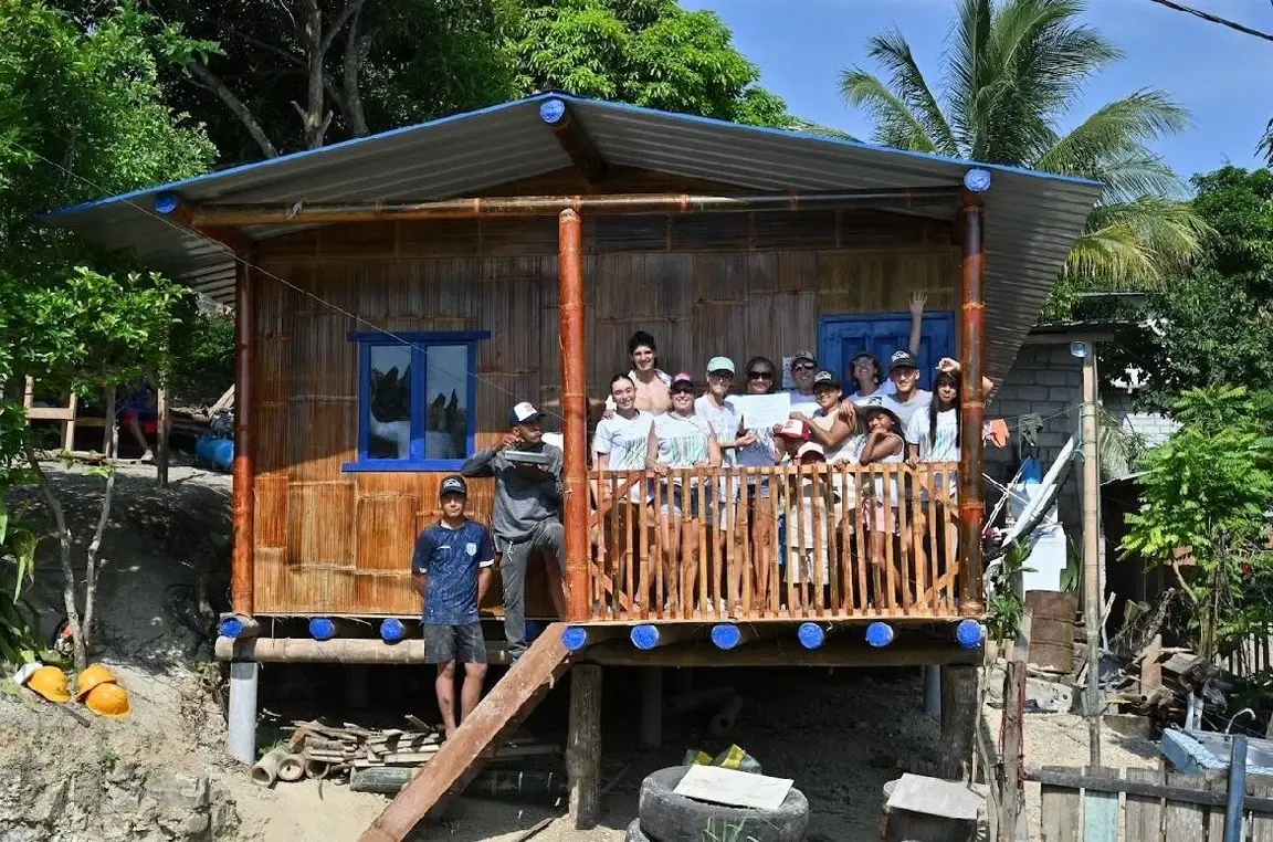 Un grupo de personas saludan desde una casa.