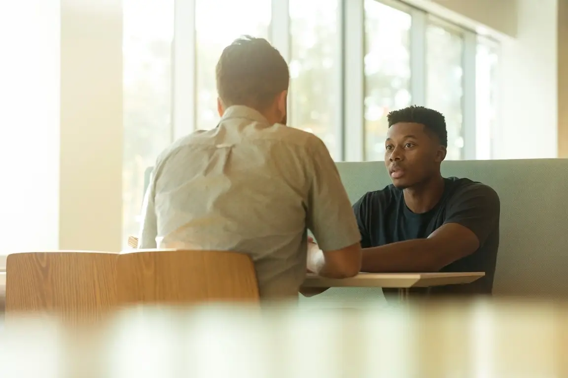 Two men sitting across from each other at a table conducting an informational interview for grad school.