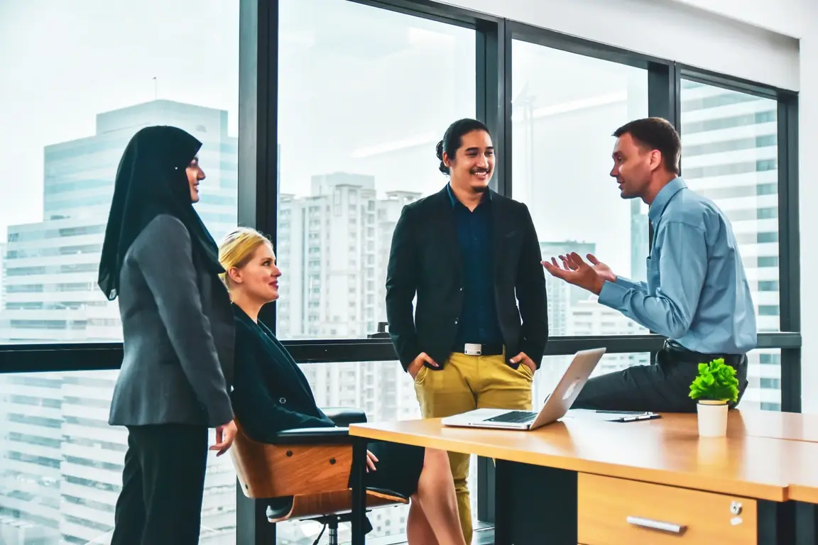 A group of co-workers talking in around an office desk.