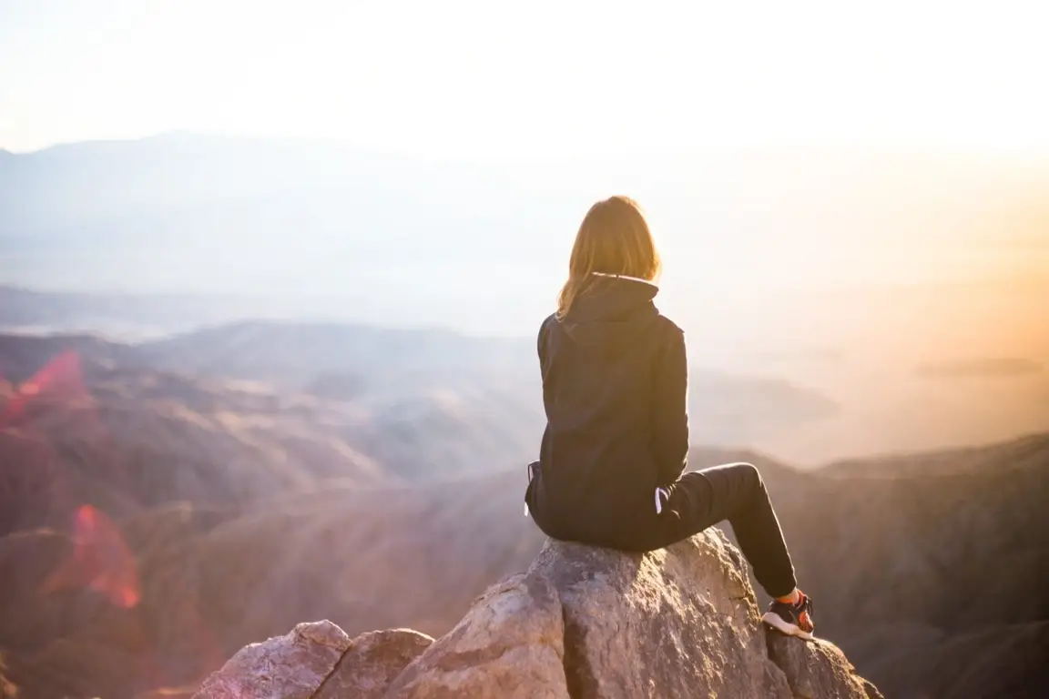 A woman sitting on a cliff.