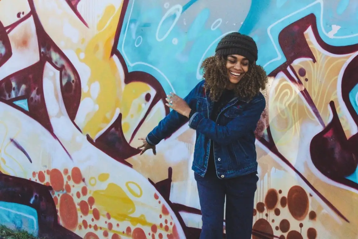 A woman standing in front of a mural.