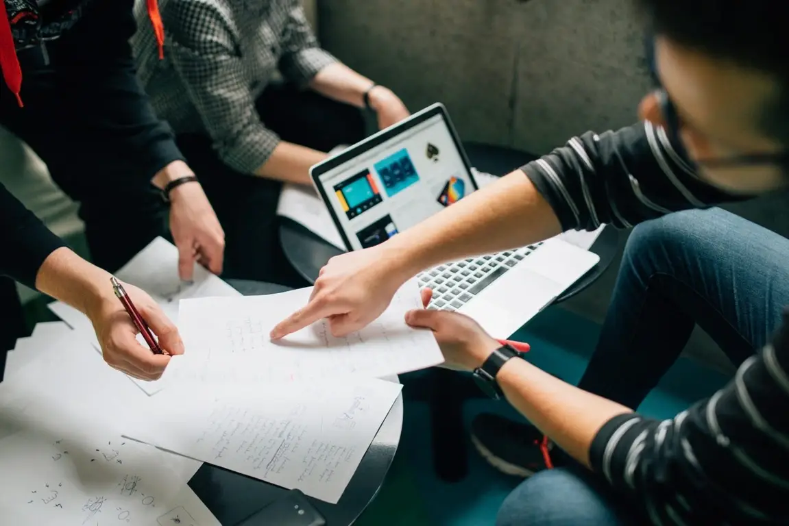 A group of people working together with a laptop and papers.