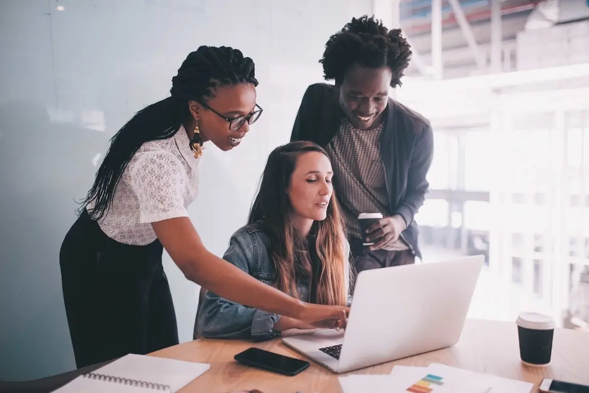 A team of professionals at an office looking over a laptop