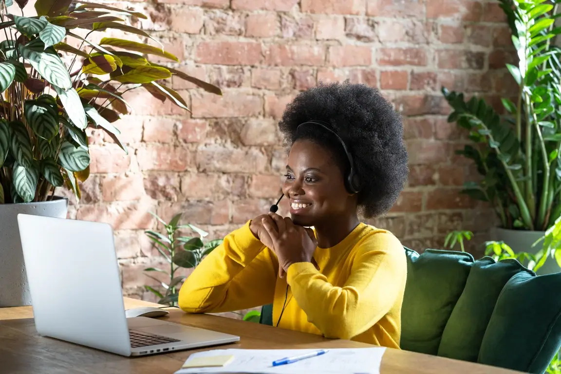 A young woman sitting at a desk with her laptop during a virtual interview.