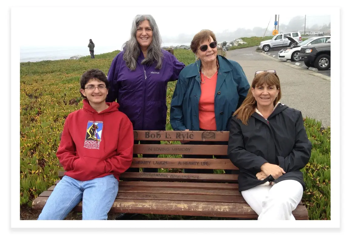 Gitta, sua filha Janine, seu neto Bennett e sua nora Susan, em um banco dedicado ao falecido marido de Gitta, Bob.