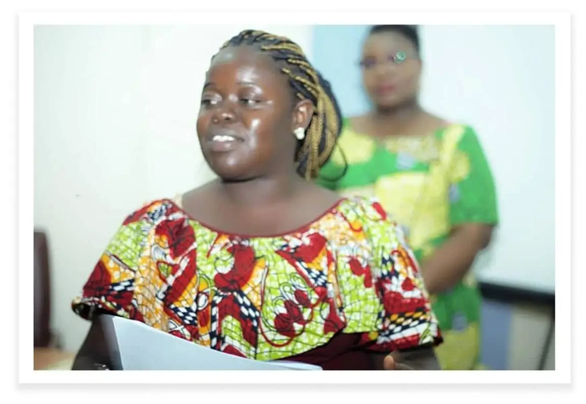 A young woman speaks in front of a room.