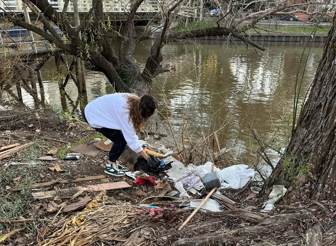 Una joven limpia las orillas de un río contaminado