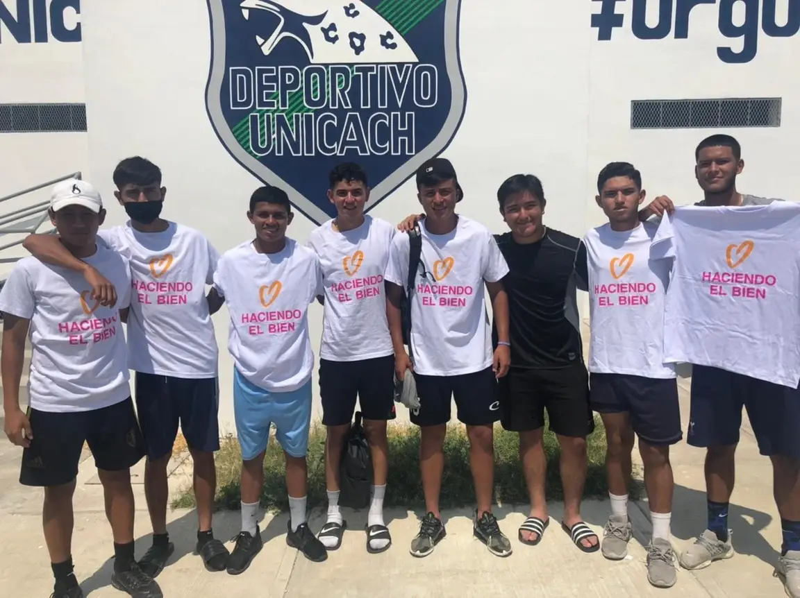 Ocho jóvenes portan y sostienen una playera del Día de las buenas acciones