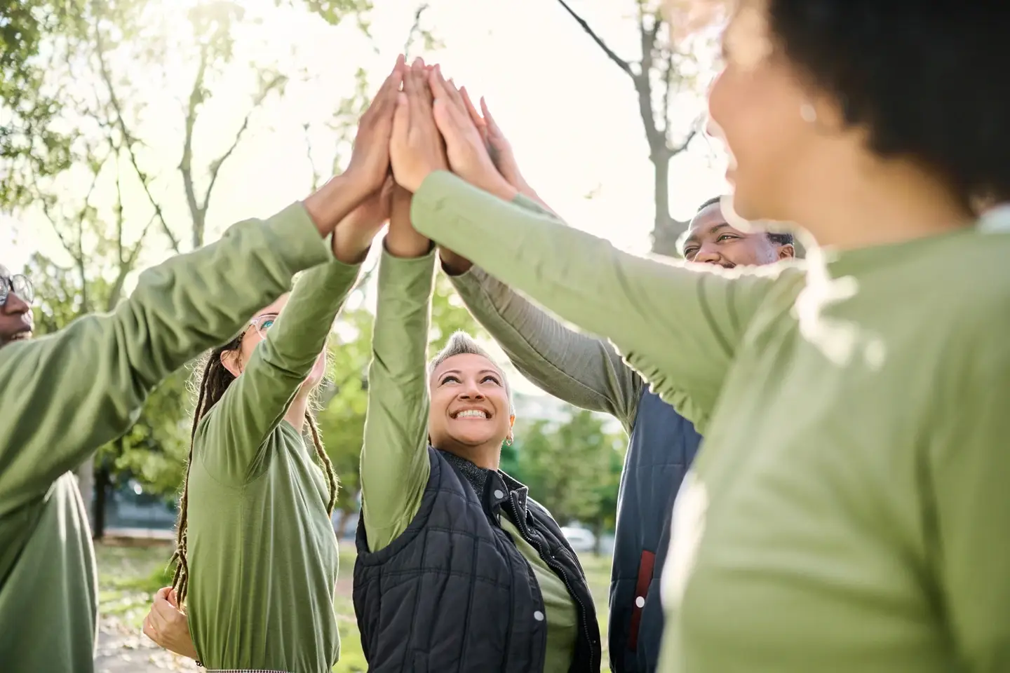 Group of volunteers high-five at a park clean up.
