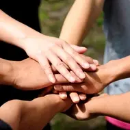 Several volunteers put their hands into a pile.