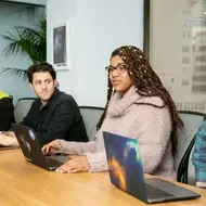 4 people with laptops, sitting at a table