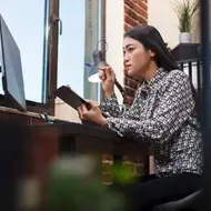 Asian woman with long hair looks intently at computer screen at the office