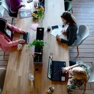 3 mulheres sentadas em uma mesa usando notebooks.