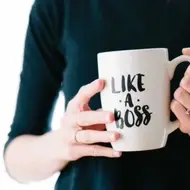 A woman holding a white mug that says, "Like a boss."