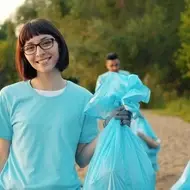 Grupo de voluntários sorrindo enquanto limpa a margem de um rio