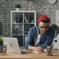 Homem trabalhando em sua mesa, fazendo anotações em um caderno