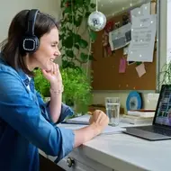 Woman working a remote nonprofit job from home, wearing headphones while sitting at her desk.