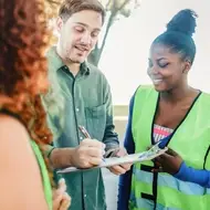 Volunteers collecting donations for an organization, asking a man to sign their clipboard