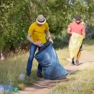 Two men collecting litter in trash bags as a part of their volunteer efforts