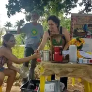 Imagen de cuatro personas: una mujer sirviendo café a otra, un hombre con una camiseta de Idealist y otra mujer sentada en la esquina de la mesa