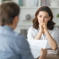 White woman considers the question about salary expectations during a job interview.
