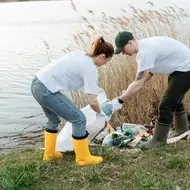 Personas recogen basura a la orilla de un lago.