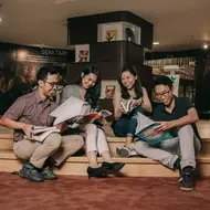 two men and women smiling and reading books