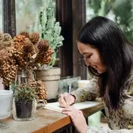 woman writing surrounded by plants
