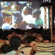 Imagem de pessoas sentadas em frente a uma projeção de um filme.