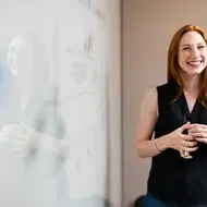 Mujer sonriendo frente a una pizarra