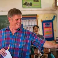 English teacher stands in a classroom, hand out to high five a student