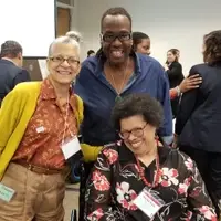 Two Black women and a Black male at a meeting