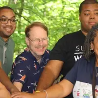 6 people outside smiling putting hands in middle
