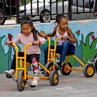 two children ride tricycles