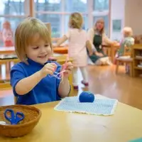 A young child in a Montessori classroom sews independently.