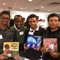 3 boys pose with their teacher and their books