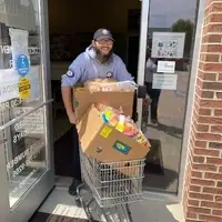 AmeriCorps Member pushing a cart of food boxes out the door