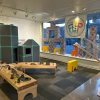 A variety of play materials are offered in a space including trains, giant magnetiles, wind tunnel and building blocks.