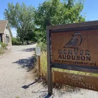 A sign outside of a stone building with a dirt path.