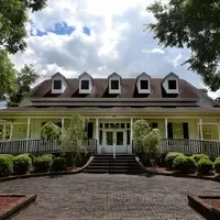 The Berkeley County Museum is a large white building with shrubbery flanking two ramps. The cloudy sky is bright behind the building.