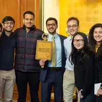 New Member at Columbia University smile and look into the camera, holding a large Phi Beta Kappa key.