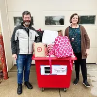 Mark and Brianna standing in front of a bin of donations