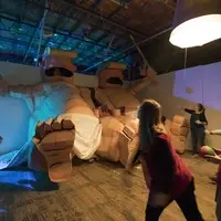 Audiences throwing balls into mouths of large, cardboard figures of the president as a baby