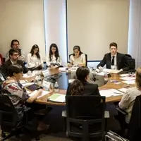 people sitting at a round table with documents on the table
