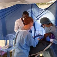 International and local dental professionals work side-by-side providing dental care to a patient during a Cheherma Foundation team-based medical camp in the Kibera community of Nairobi, Kenya.