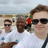 Joseph Odoteye from Pro-Passion Projects stands in the middle at the Independence Arch of Ghana in Accra, joined by James from Oxford University, a journalism volunteer, and Ian from Gonzaga University, a law and human rights volunteer. All three are wearing Pro-Passion Projects T-shirts during their Accra city tour, smiling proudly in front of the iconic Independence Arch, a symbol of Ghana’s freedom and national pride. The sunny day and historic monument form a beautiful backdrop that highlights the spirit of teamwork, cultural exchange, and learning. This image reflects the volunteers’ excitement and unity as they explore Ghana’s heritage while engaging in impactful community projects with Pro-Passion Projects