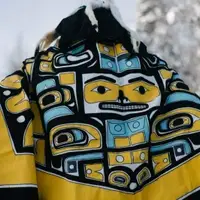 A Wet'suwet'en leader stands with their back to the camera wearing their traditional regalia