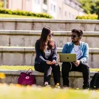 Students sitting on steps looking at a laptop