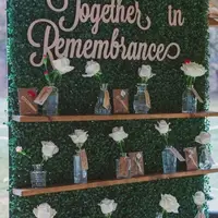 Flower wall with Together in Remembrance titled over it and vases holding flowers with names of babies gone too soon.