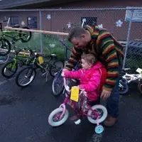 A dad helps his little girl test ride a bike at the Kids Swap